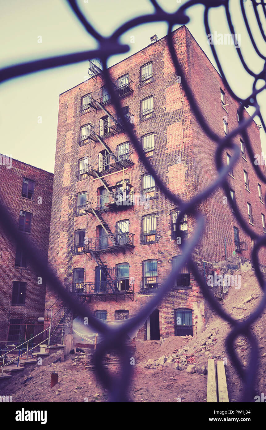 Si tratta di un vecchio edificio con il fuoco sfugge visto attraverso una recinzione, dai toni di colore immagine, New York City, Stati Uniti d'America. Foto Stock