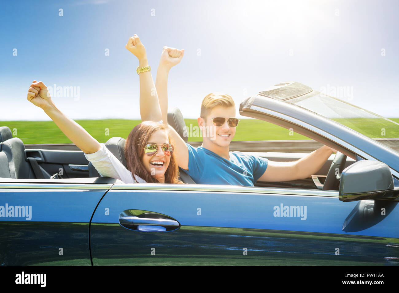 Coppia giovane indossando occhiali da sole che viaggiano in auto Foto Stock