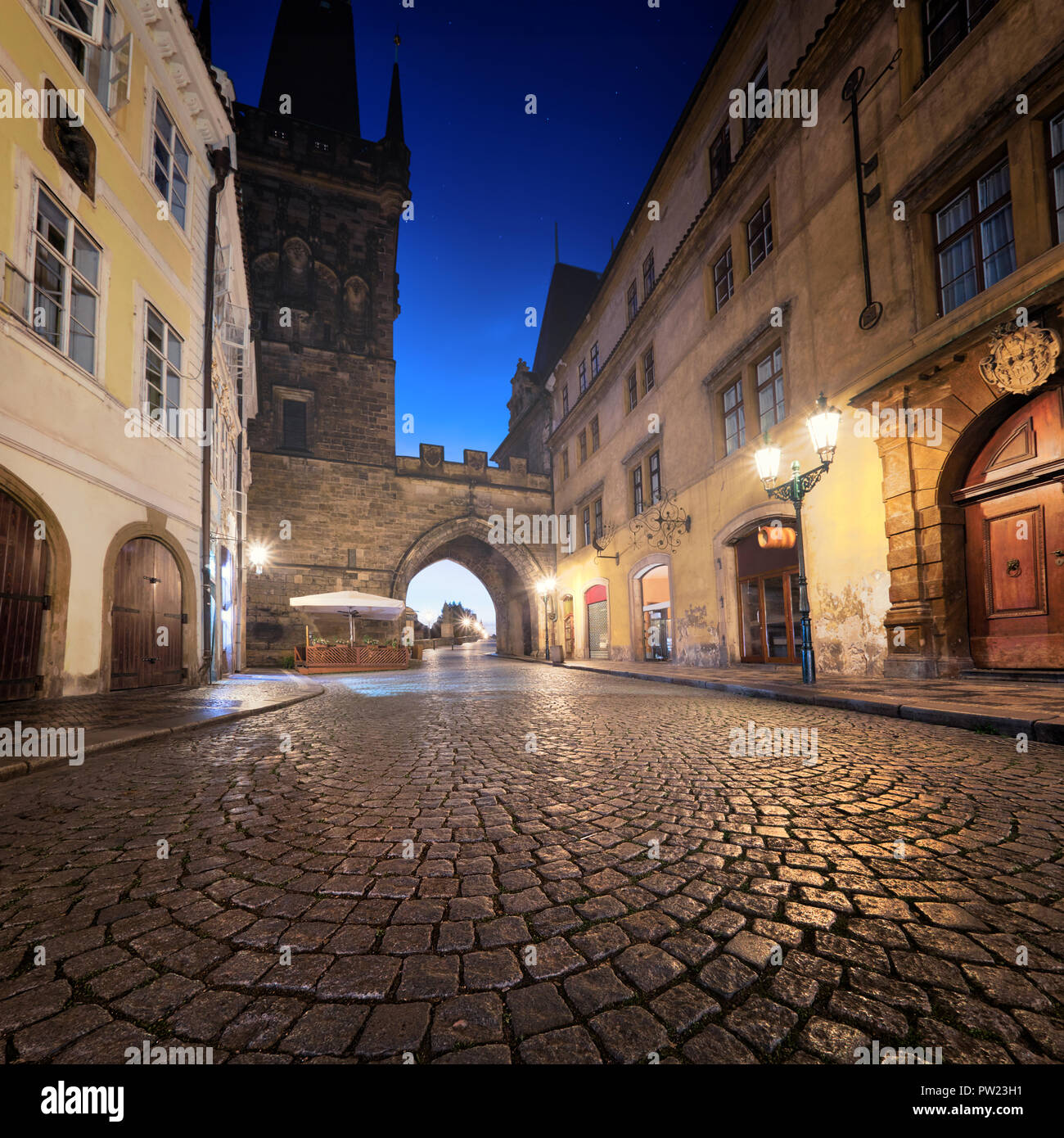 Via medievale che conducono verso la Città Minore torre del ponte verso il Ponte di Carlo su una notte piovosa a Praga, Repubblica Ceca Foto Stock