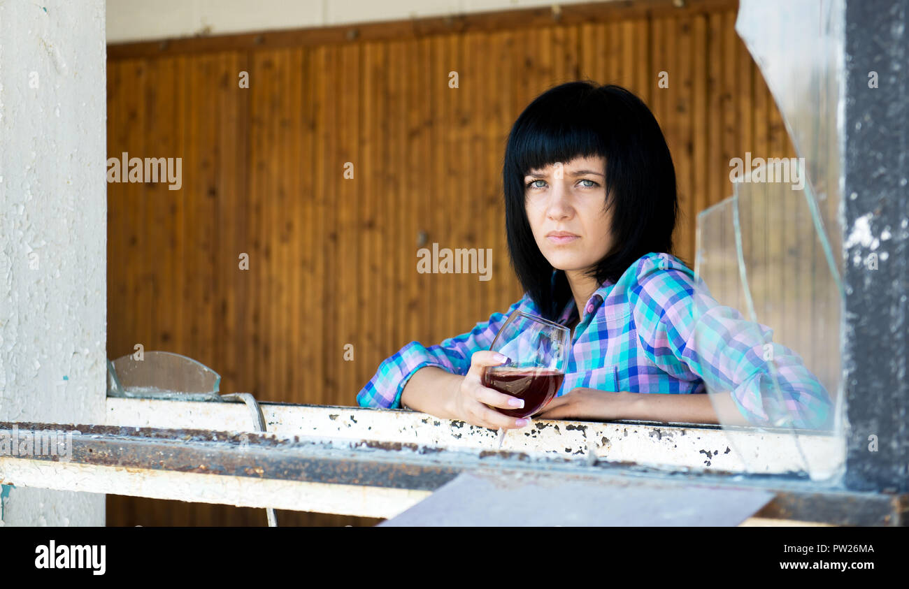 La giovane donna con un bicchiere di vino nel distrutto edificio Foto Stock