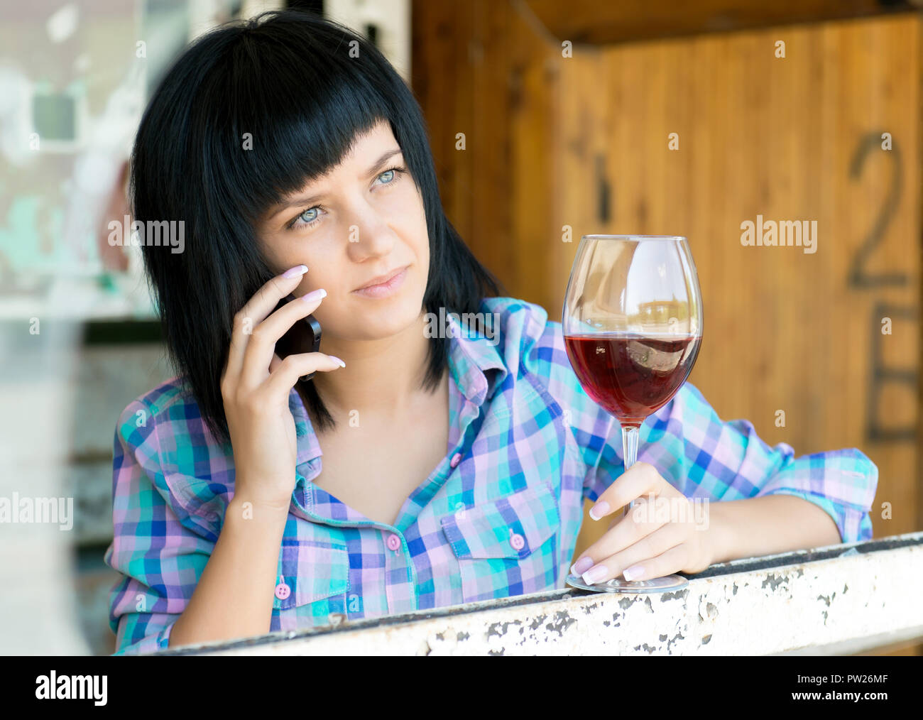 Parla la giovane donna con un bicchiere di vino telefono Foto Stock