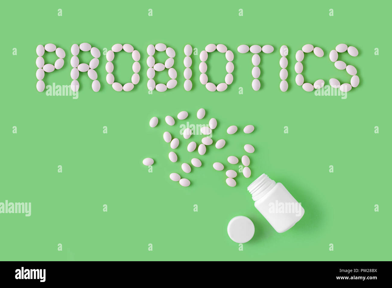Probiotici parola fatta di pillole su sfondo verde. Appartamento laico, vista dall'alto, copia gratuita dello spazio. Foto Stock