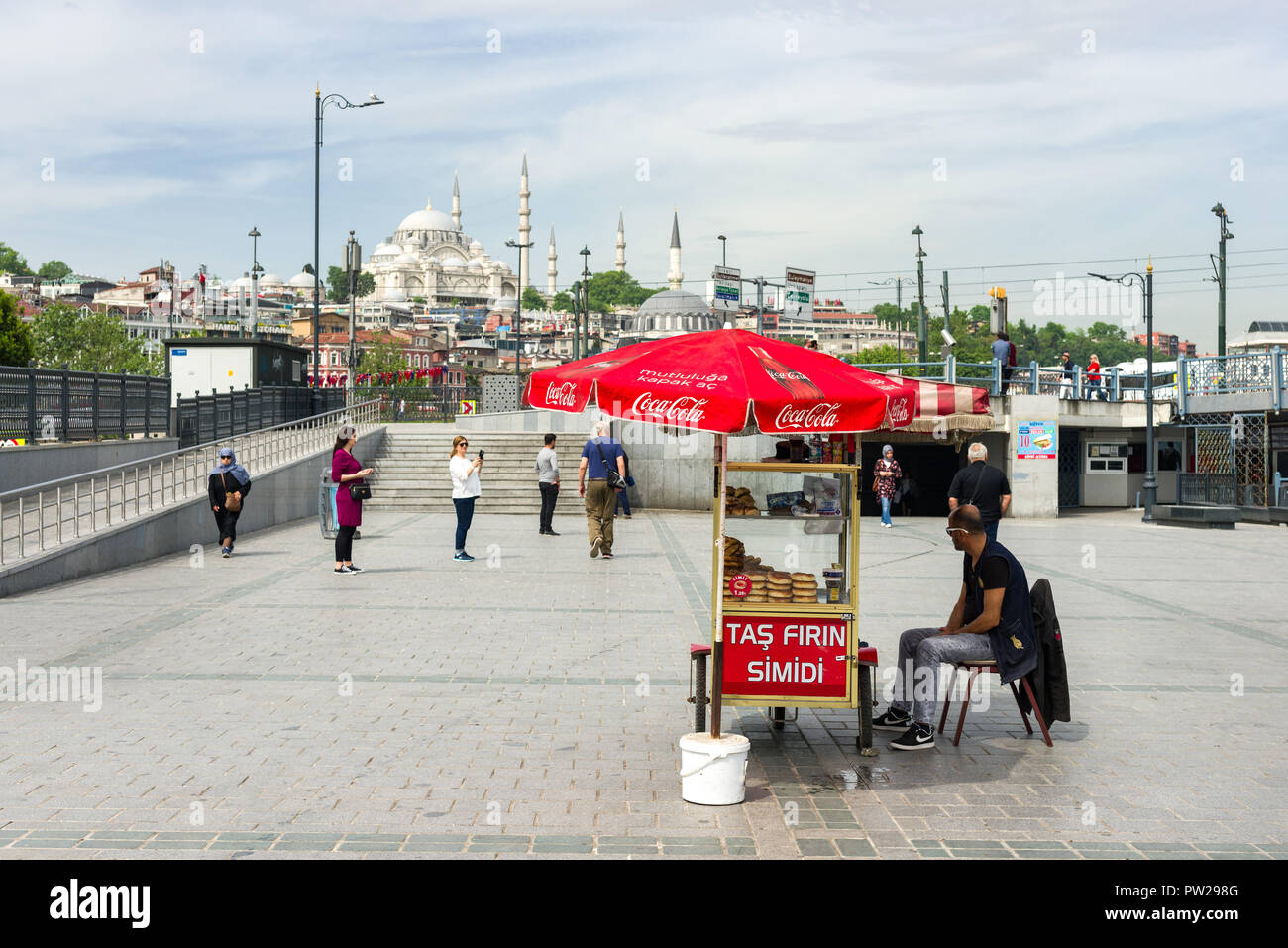 Un uomo si siede dietro il suo piccolo food cart che dispone di bagno turco pretzel o bagel (simidi o simit) per la vendita, Istanbul, Turchia Foto Stock