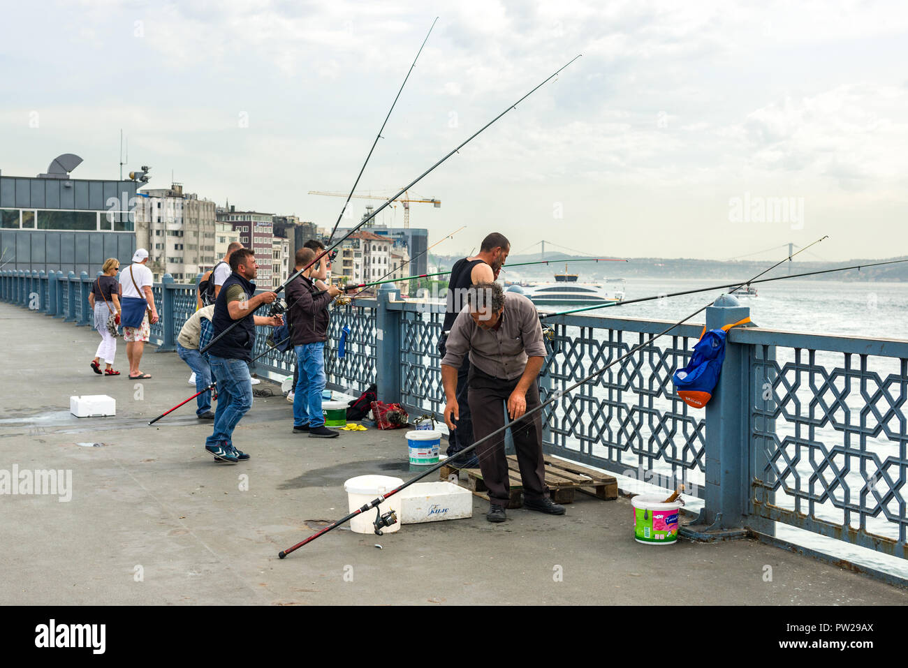 Un gruppo di pescatori di sostare sul Ponte di Galata con le loro canne da pesca oltre il lato, Istanbul, Turchia Foto Stock