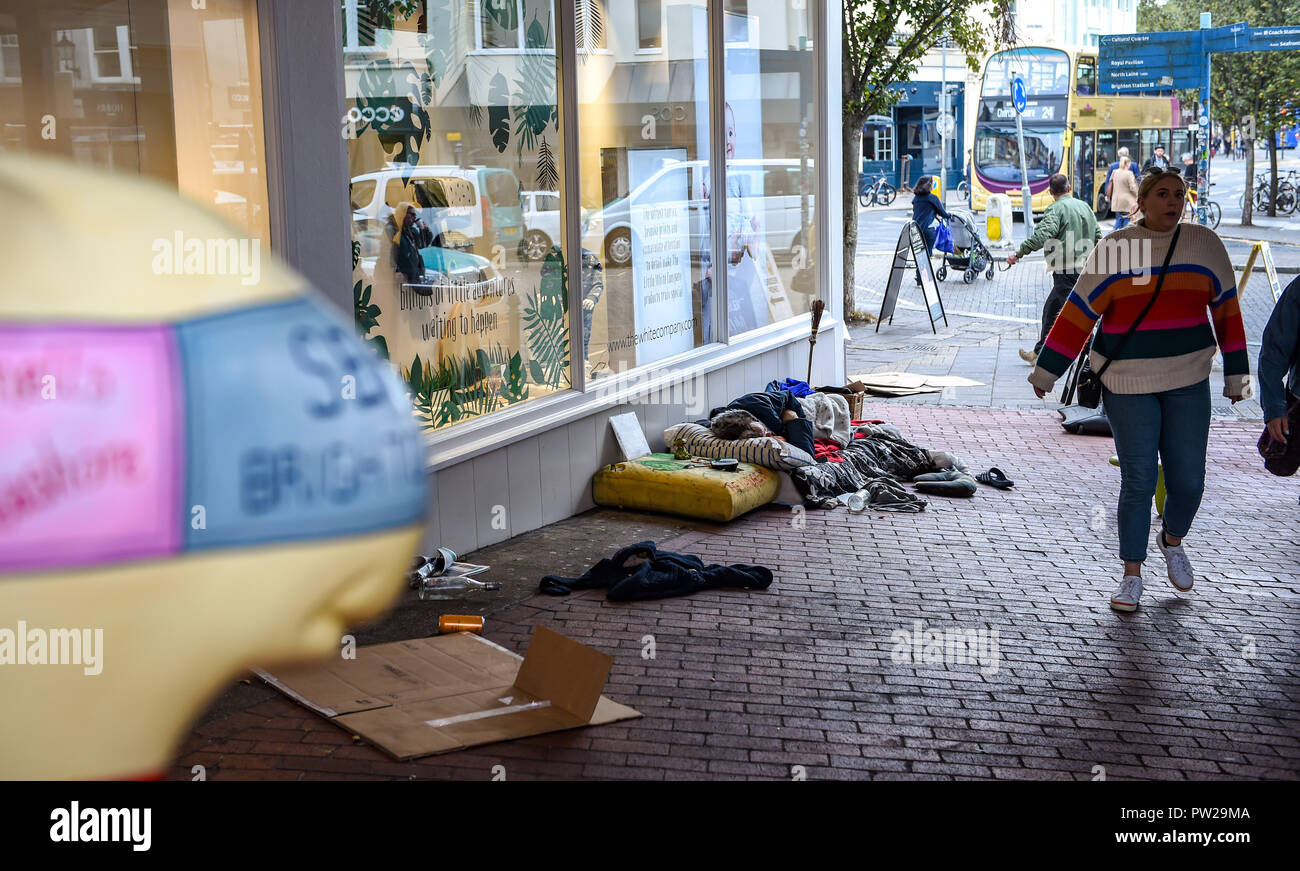 Brighton Regno Unito 11 ottobre 2018 - persona senzatetto per le strade di Brighton accanto a una scultura Snailspace Foto Stock