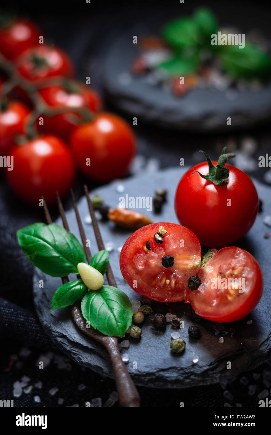 Frische Cherry Tomaten mit Basilikum auf Schiefer angerichtet Foto Stock