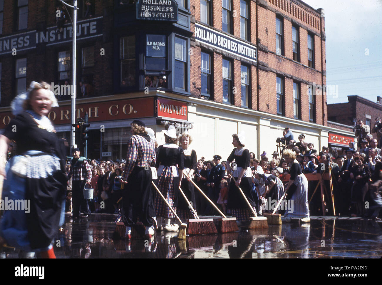 1940s, storico, donne americane in costume con spazzole in strada, prendendo parte del Maggio 'Tulip Time' Festival nella città di Olanda, Michigan, Stati Uniti d'America, una celebrazione della città patrimonio olandese. Fondata da Calvanist olandese dei coloni nel 1847, la città è un avamposto della cultura olandese e tradizione nel mezzo del Midwest americano ed è noto per le sue chiese, di cui essi sono circa 170 in la maggiore area di Olanda. Foto Stock