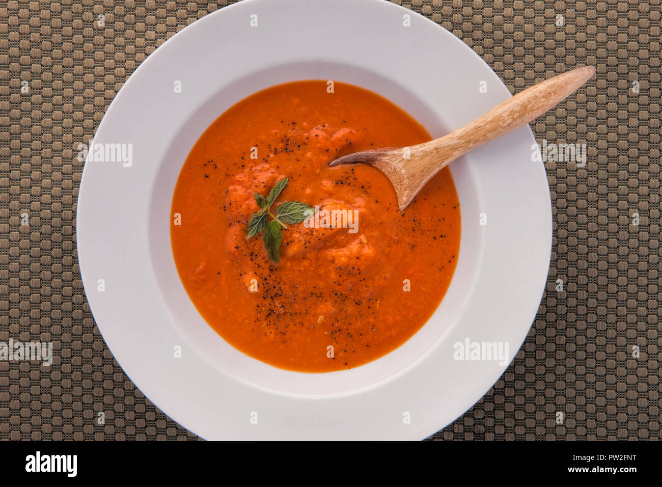 Una panoramica di peperoncino minestra in un bianco rin ciotola con un cucchiaio di legno Foto Stock