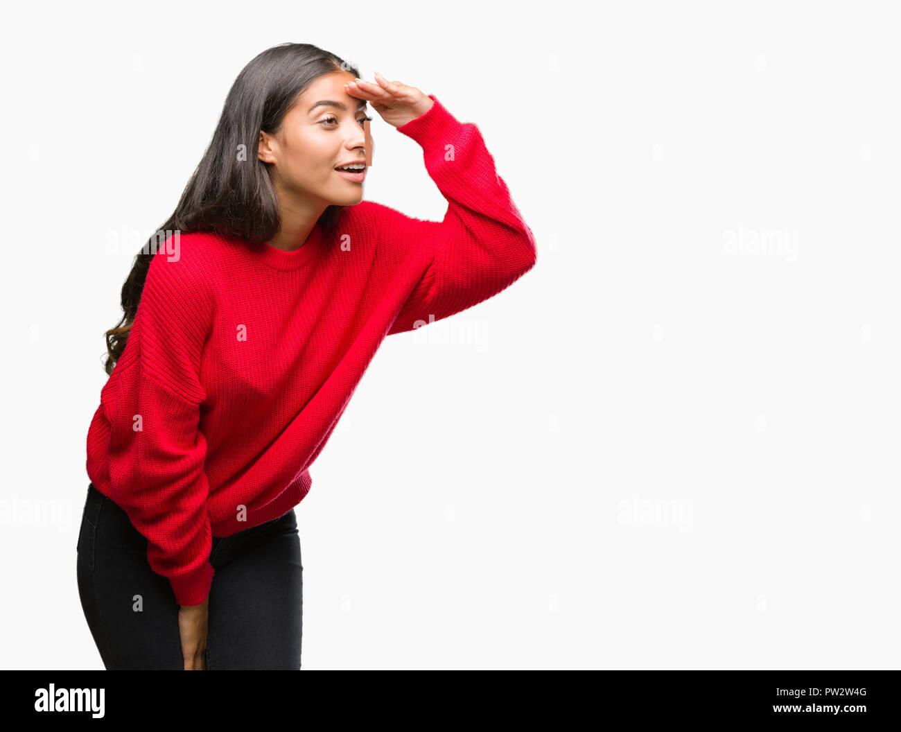 Giovane bella donna araba che indossa un maglione invernale su sfondo isolato molto felice e sorridente guardando lontano con la mano sopra la testa. Ricerca conc Foto Stock