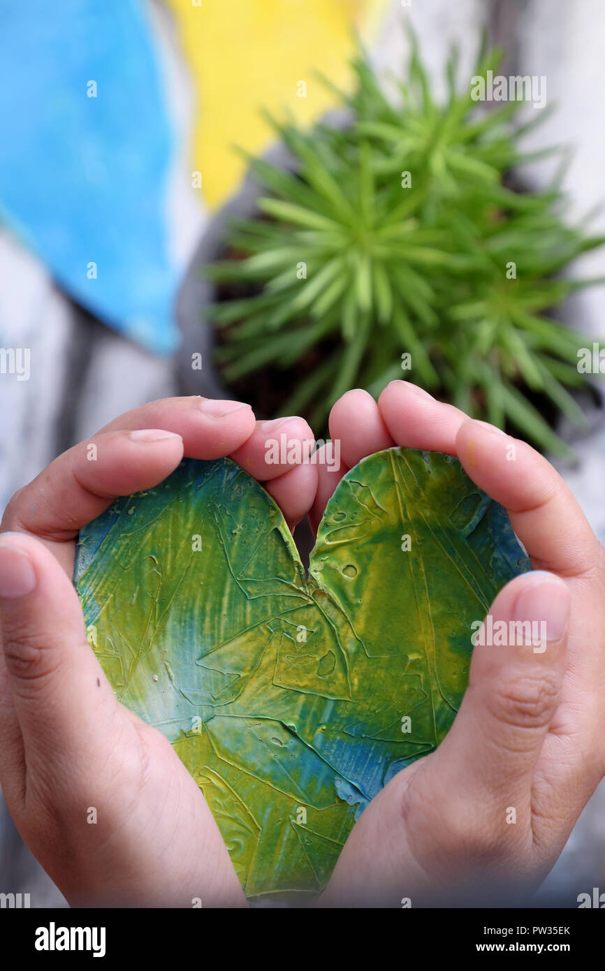 Mano umana tenere il cuore in mani con un altro a fondo, due cuori in giallo e blu con messaggio di ringraziamento Foto Stock