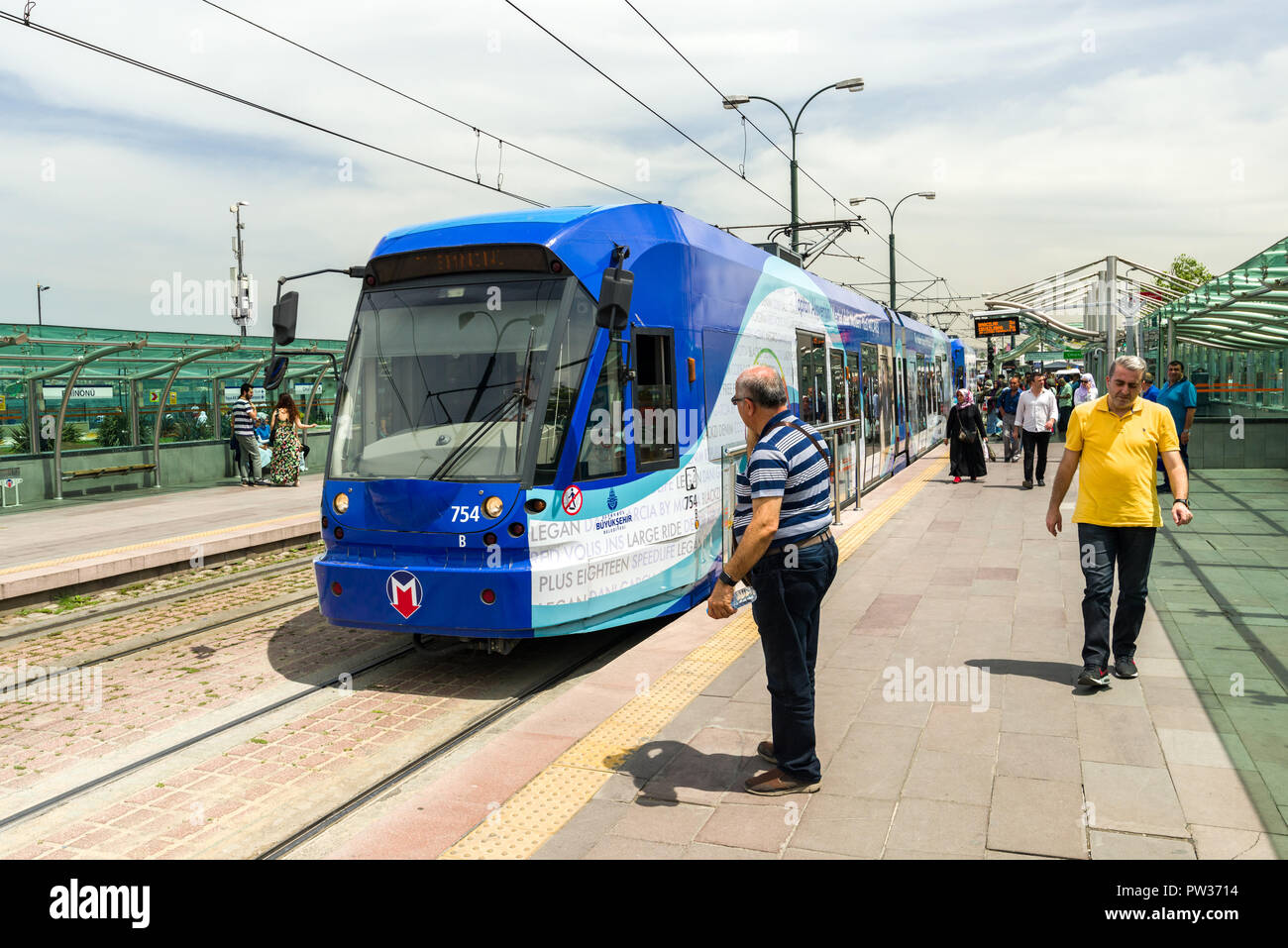 Persone in piedi sulla piattaforma come un T1 metro tram tira in alla stazione, Istanbul, Turchia Foto Stock