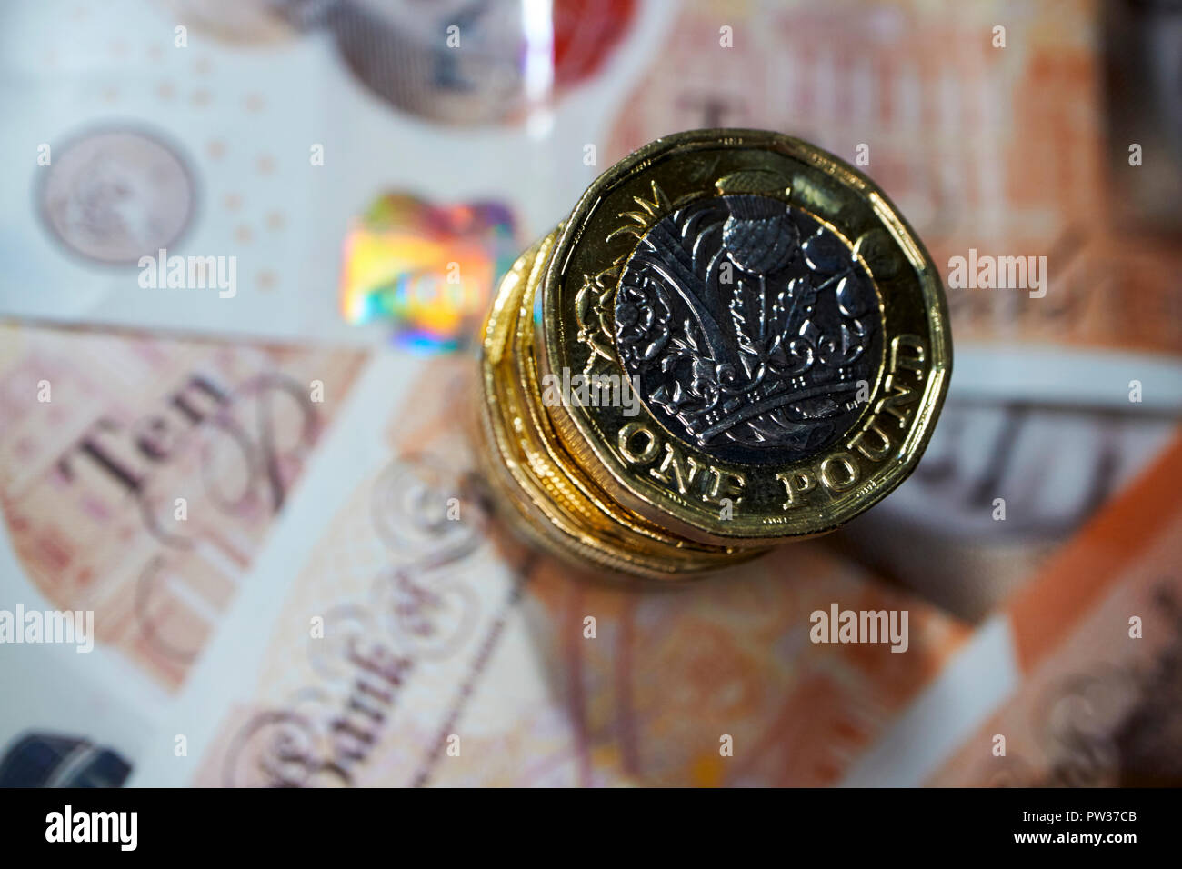 Pila di libbra di monete su plastica dieci pound note Foto Stock