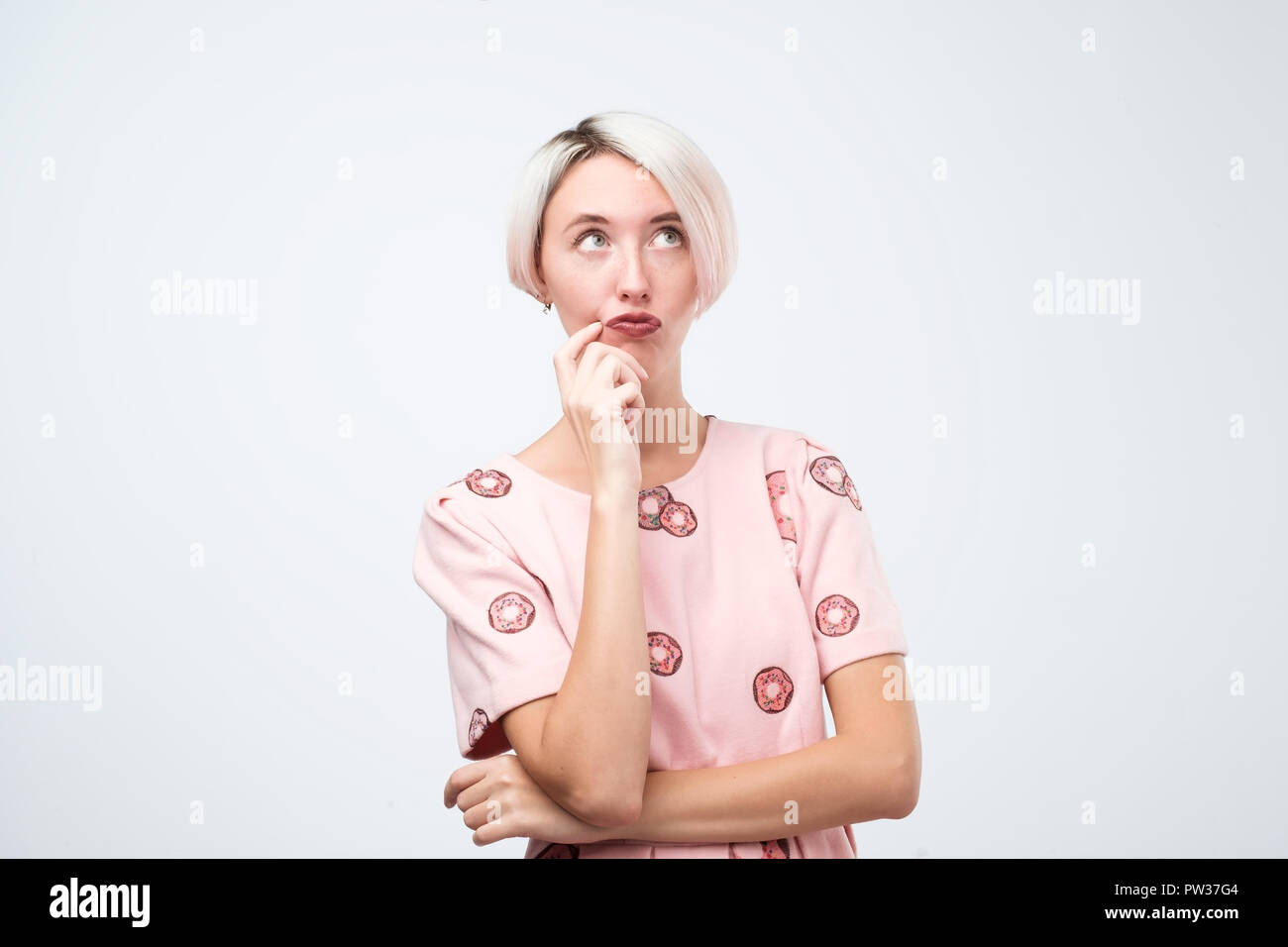 Carino giovane donna in abito rosa è pensando a qualcosa. Foto Stock
