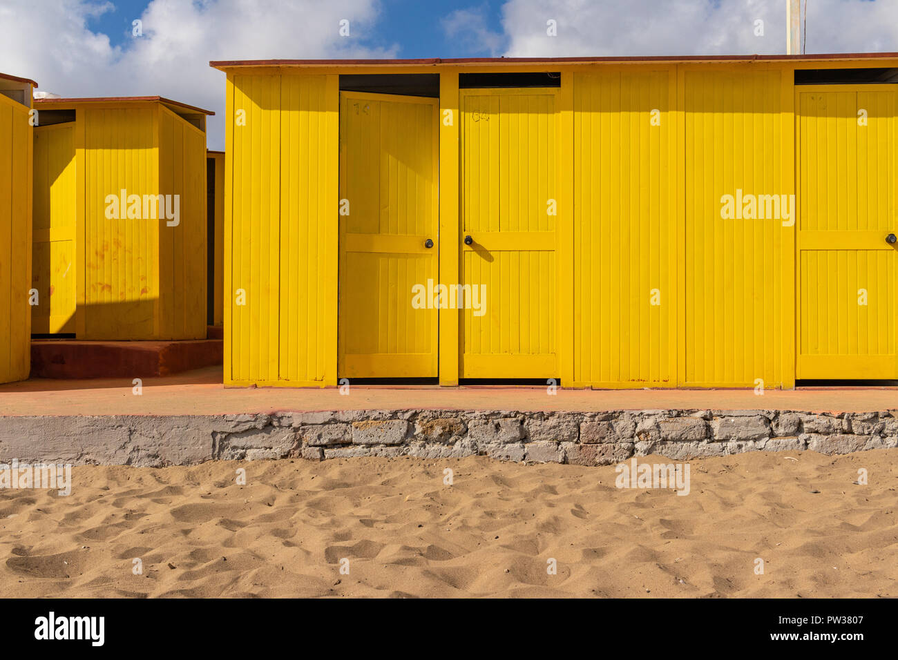 Bel colore giallo case balneare sulla spiaggia sabbiosa. Rifugi vuota su un soleggiato ma moody giorno. Architettura balneare, vernice colorata, del tipo a labirinto labyrint. Foto Stock