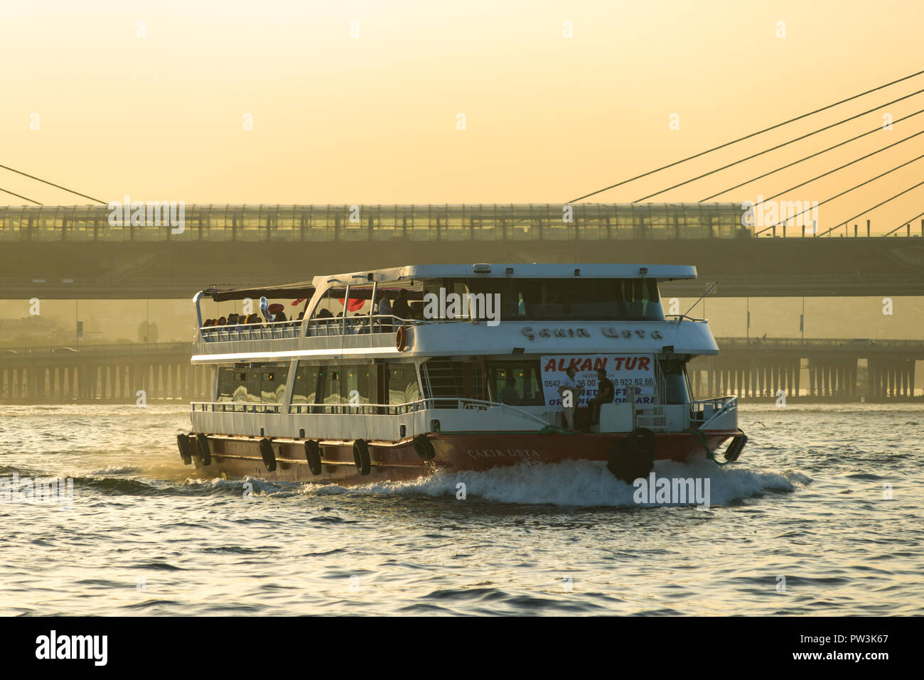 La Haliç Golden Horn Metro ponte con il traghetto a vela in primo piano al tramonto, Istanbul, Turchia Foto Stock