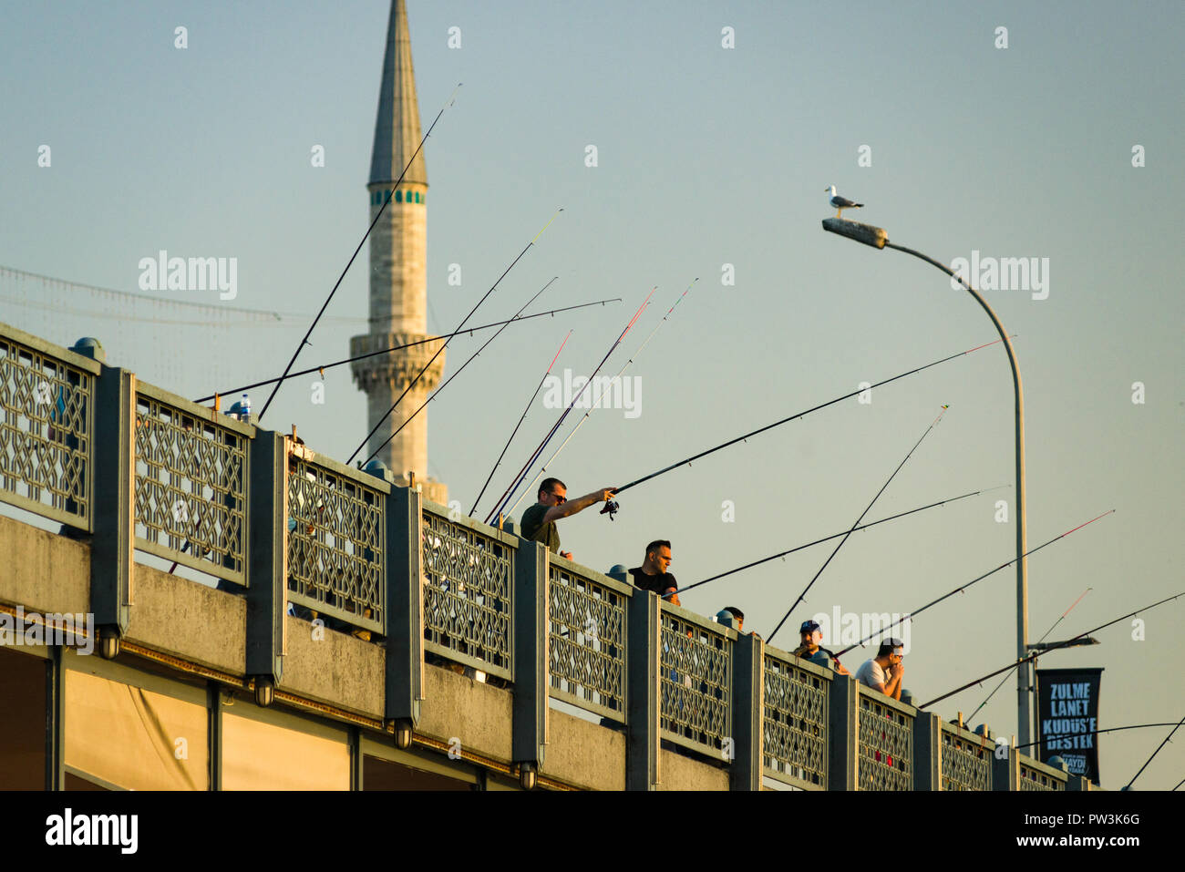 I pescatori pesca dal ponte Galata al tramonto con minareti in background, Istanbul, Turchia Foto Stock