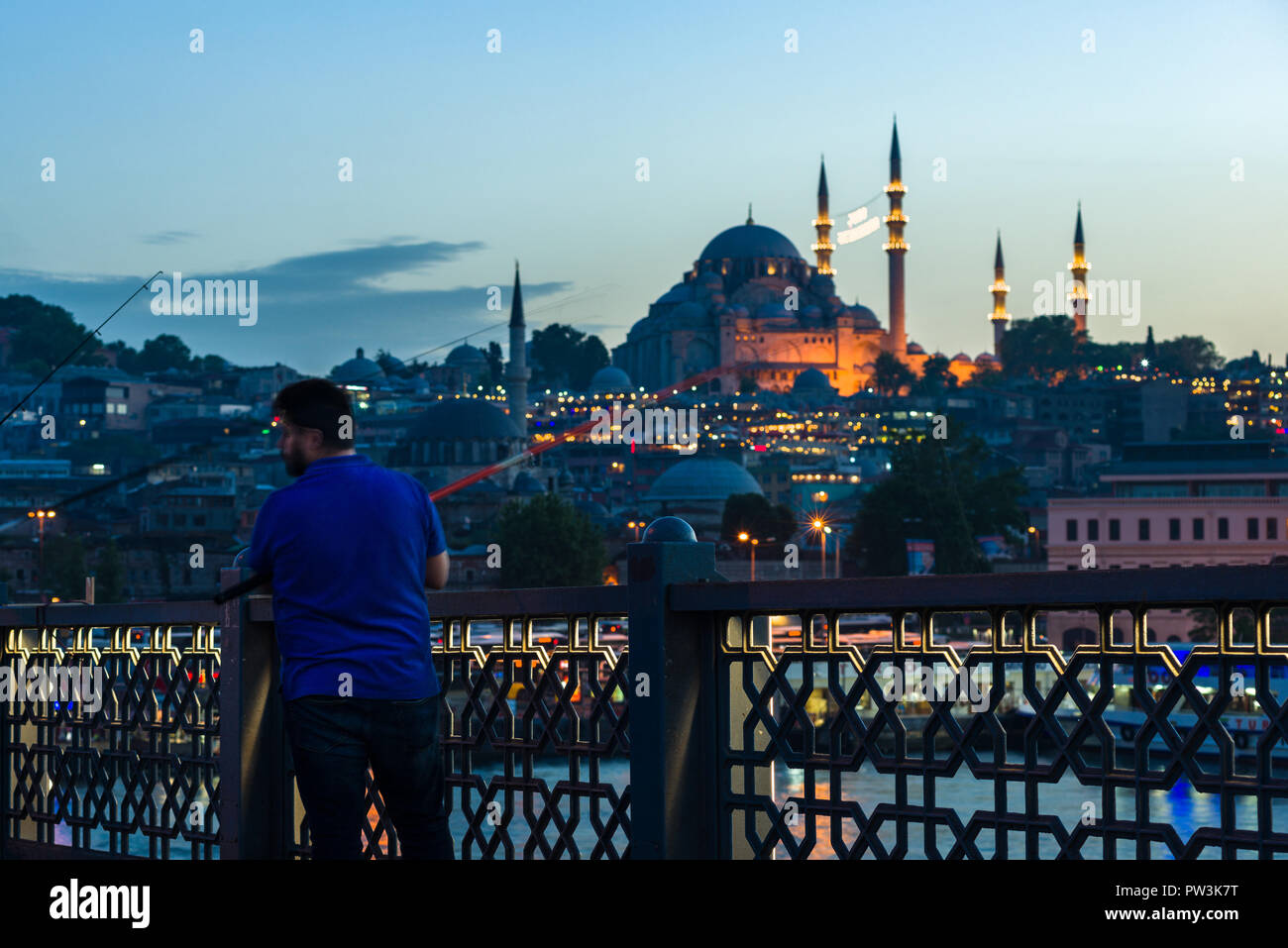 Un pescatore di pesci da Ponte Galata al tramonto con la moschea di Suleymaniye in background, Istanbul, Turchia Foto Stock