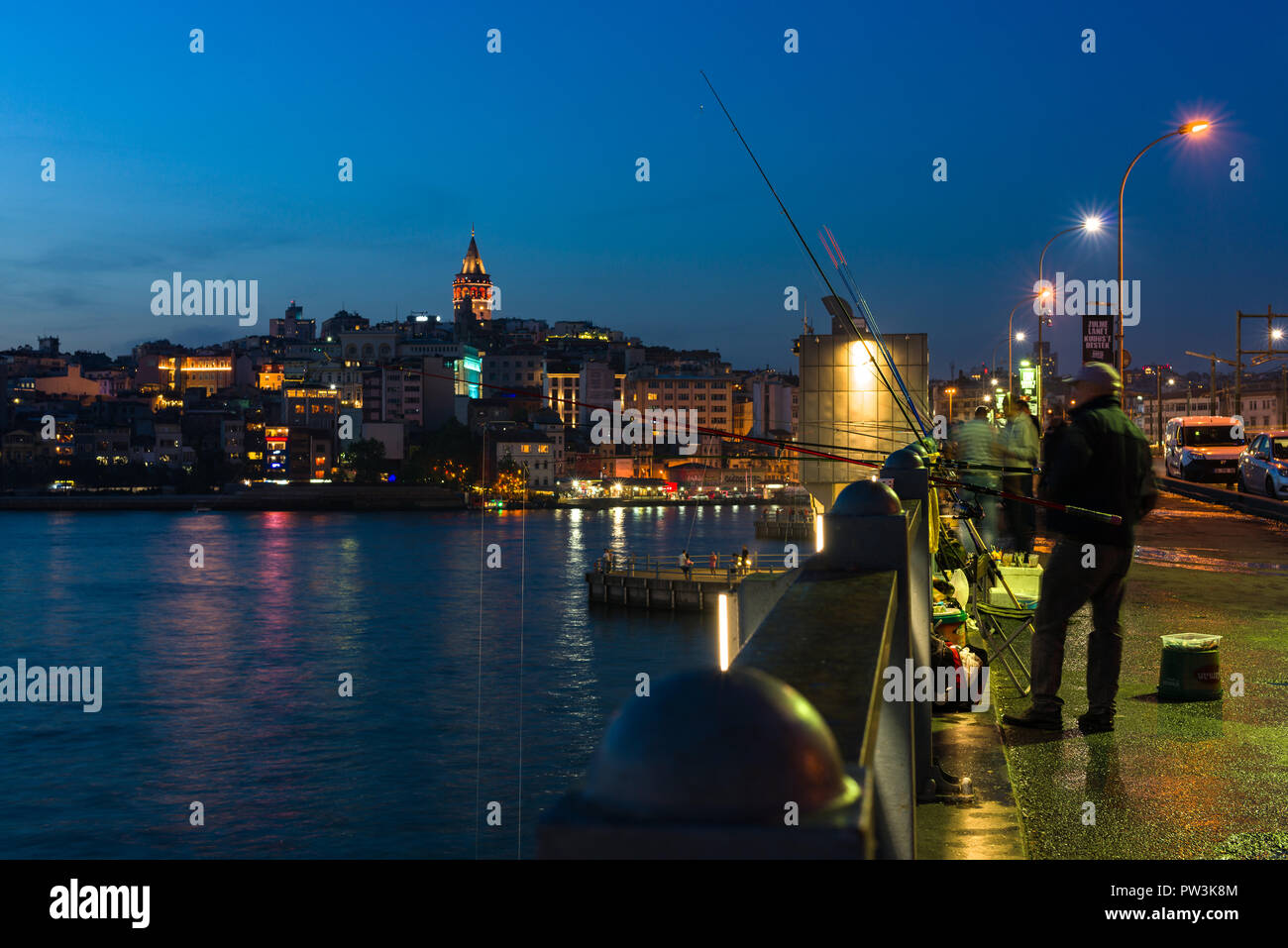Un pescatore di pesci da Ponte Galata al tramonto con Torre Galata e Karakoy in background, Istanbul, Turchia Foto Stock