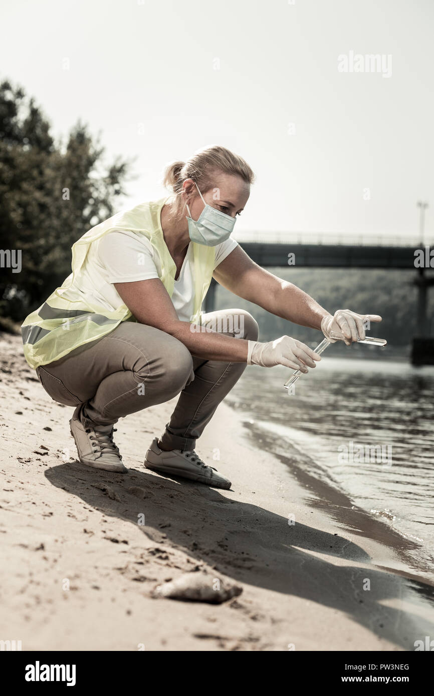 Biondo e ispettore sanitario che indossa pantaloni beige lavorando vicino al fiume Foto Stock