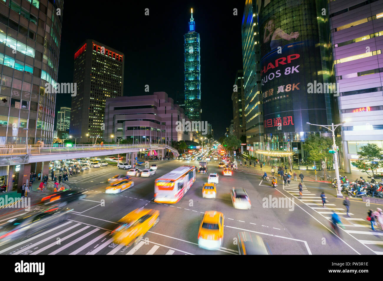 Taiwan, Taipei, traffico davanti a Taipei 101 in corrispondenza di un centro occupato intersezione nel distretto di Xinyi Foto Stock