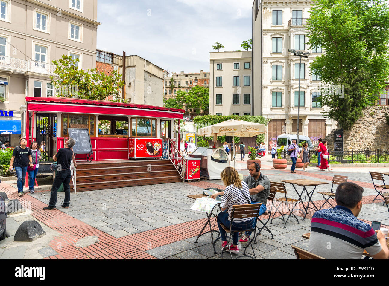 La gente seduta da un tram rosso convertito in una caffetteria vicino alla Torre di Galata, Istanbul, Turchia Foto Stock
