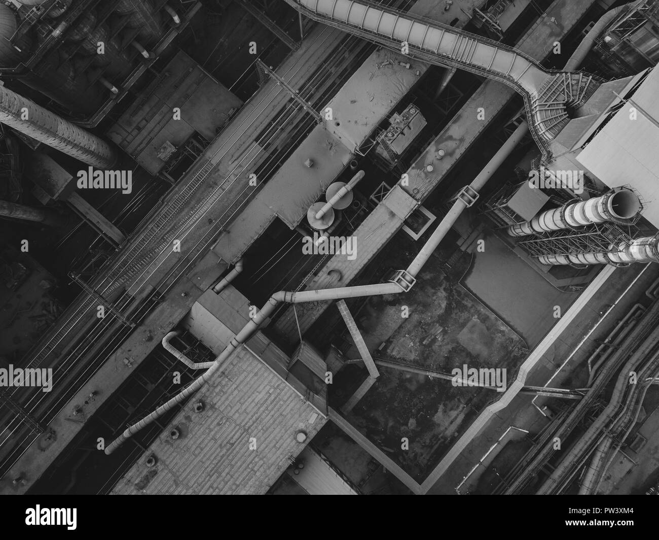 Drone vista dall'alto in basso di stile industriale nella zona con vecchie costruzioni in metallo e sistema di trasporto; tubi e camini sullo sfondo; aria polluti Foto Stock