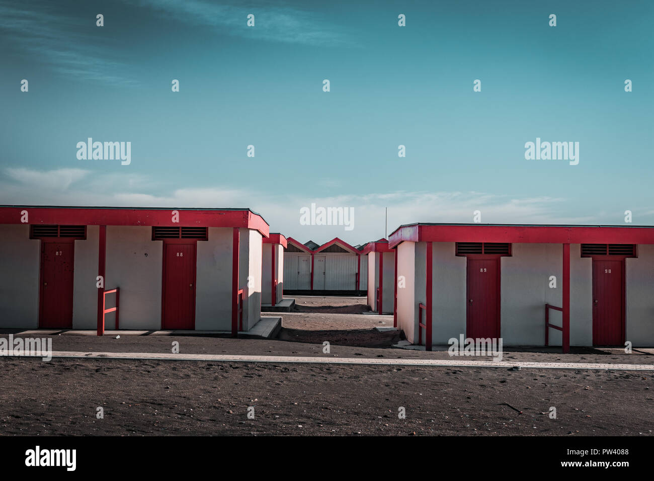 Bella rossa la balneazione case sulla spiaggia sabbiosa. Rifugi vuota su un soleggiato ma moody giorno. Architettura balneare, vernice colorata, maze come labirinto. Da solo. Foto Stock