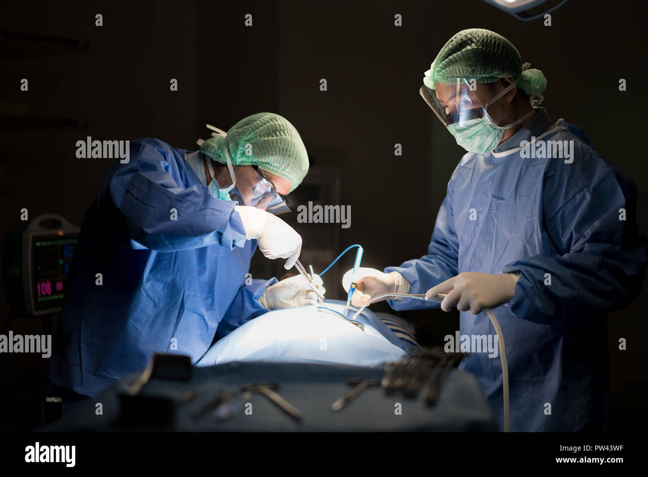 Asian medico e un assistente in sala operatoria per chirurgia vascolare venosa clinica di chirurgia in ospedale. Foto Stock