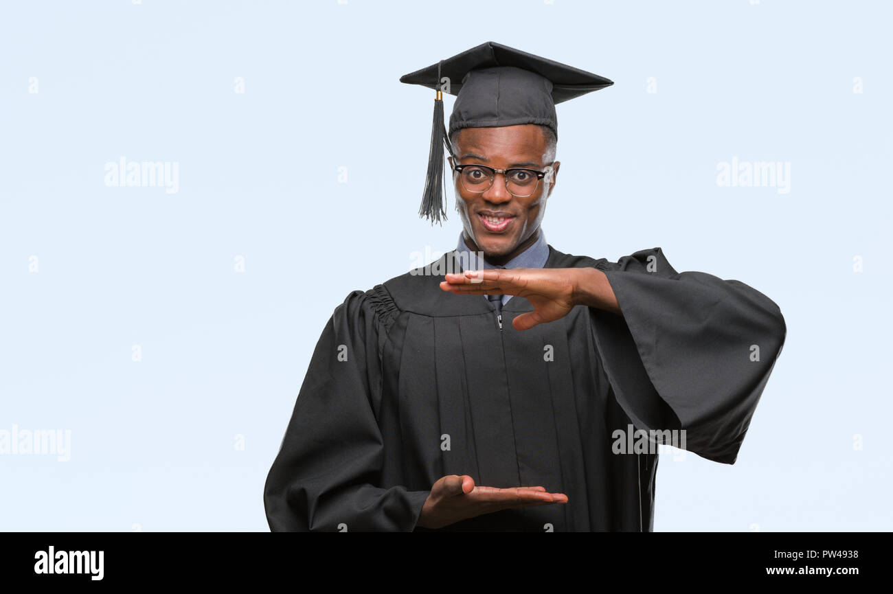 Giovane laureato americano africano uomo su sfondo isolati gesti con le mani che mostra grande e taglia grande segno, misurare il simbolo. Sorridente guardando Foto Stock