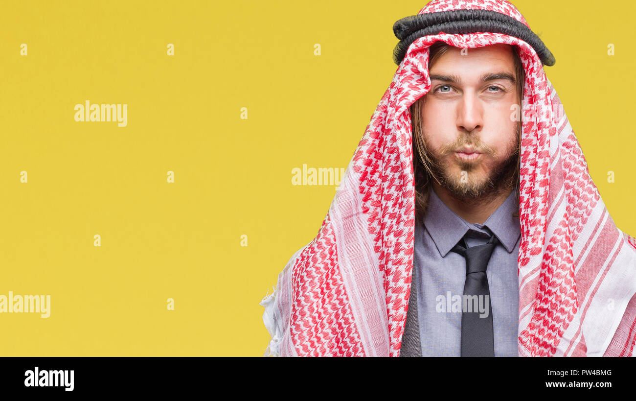 Giovane bello arabian uomo con capelli lunghi che indossa keffiyeh su sfondo isolato puffing guance con faccia buffa. Bocca gonfiato con aria, crazy exp Foto Stock