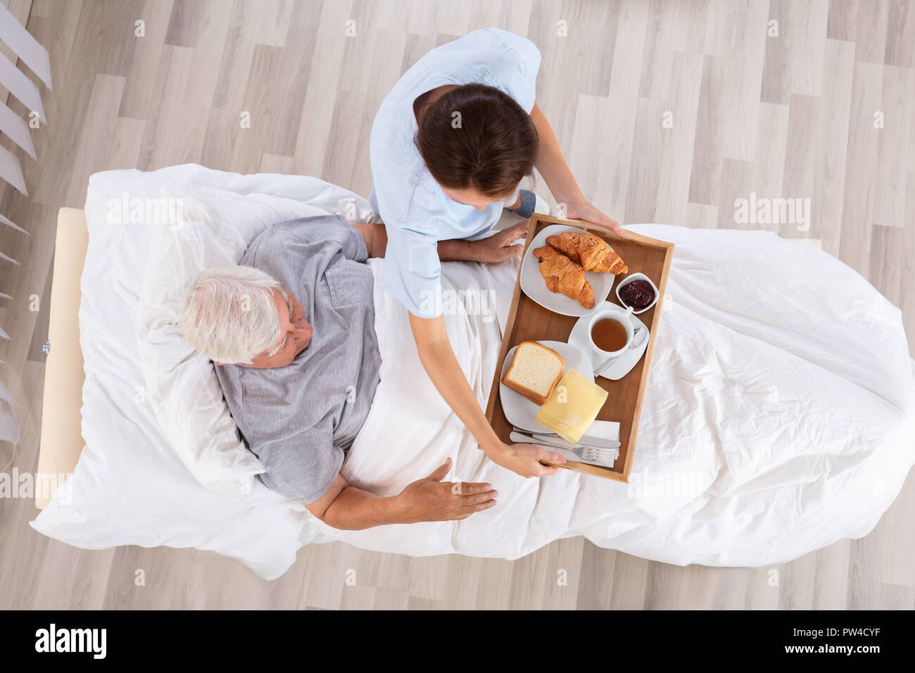 Vista aerea di infermiera femmina che serve cibo a Senior paziente di sesso maschile in clinica Foto Stock