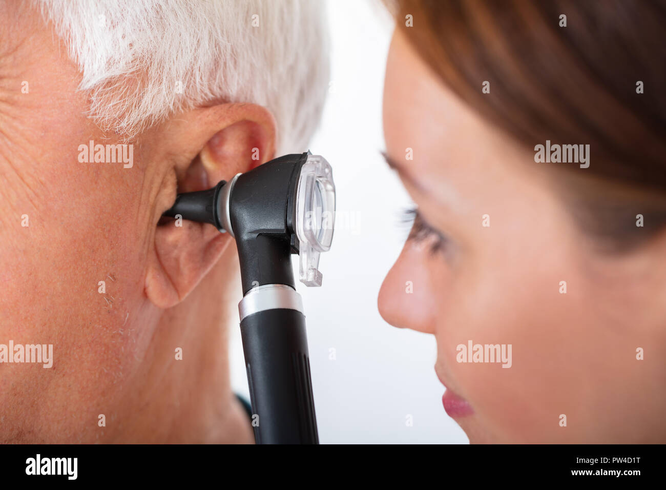 Close-up di un medico donna esame maschio Senior orecchio del paziente con otoscopio Foto Stock