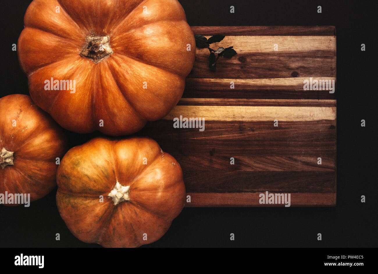 Vista dall'alto di zucche sulla tavola di legno su sfondo nero. Halloween lay piatto concept design. Foto Stock