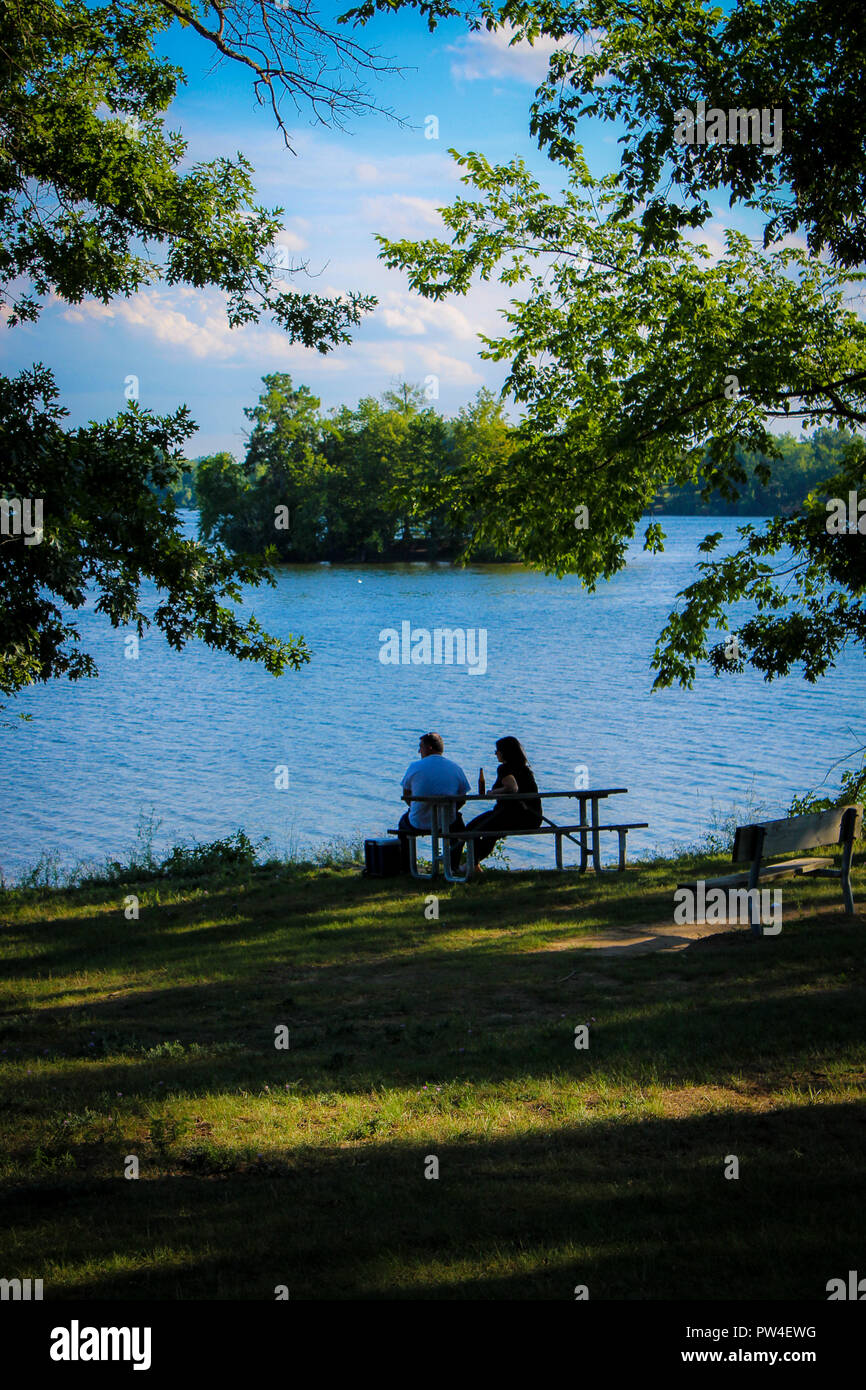 Un giovane si trova sulle sponde di un lago di trascorrere del tempo insieme con alberi in estate del Michigan vicino a Detroit Foto Stock