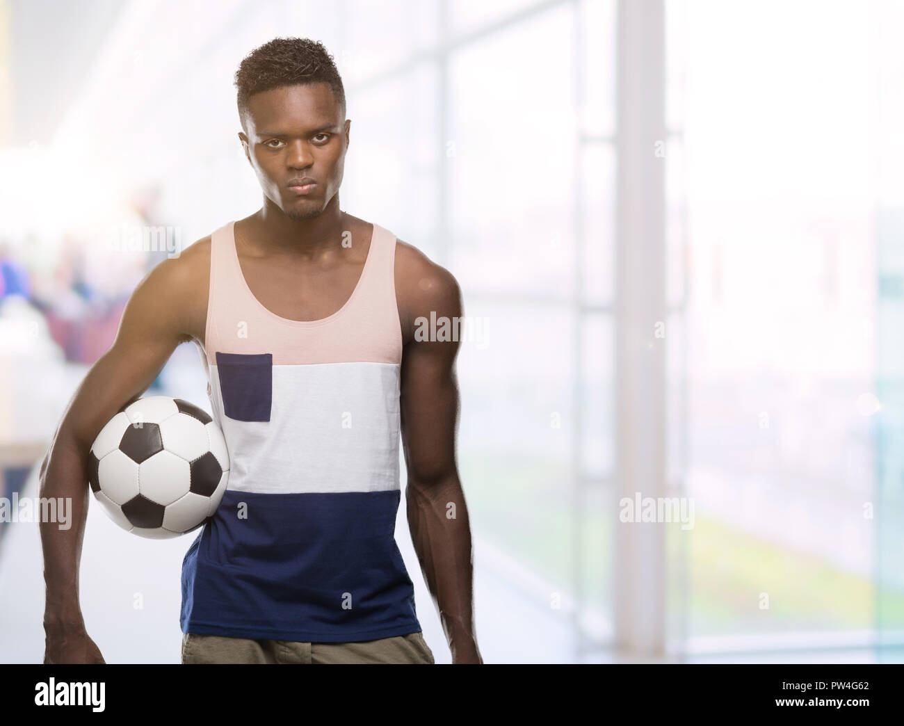 Giovane americano africano uomo azienda soccer football palla con un fiducioso espressione sul viso intelligente pensare grave Foto Stock