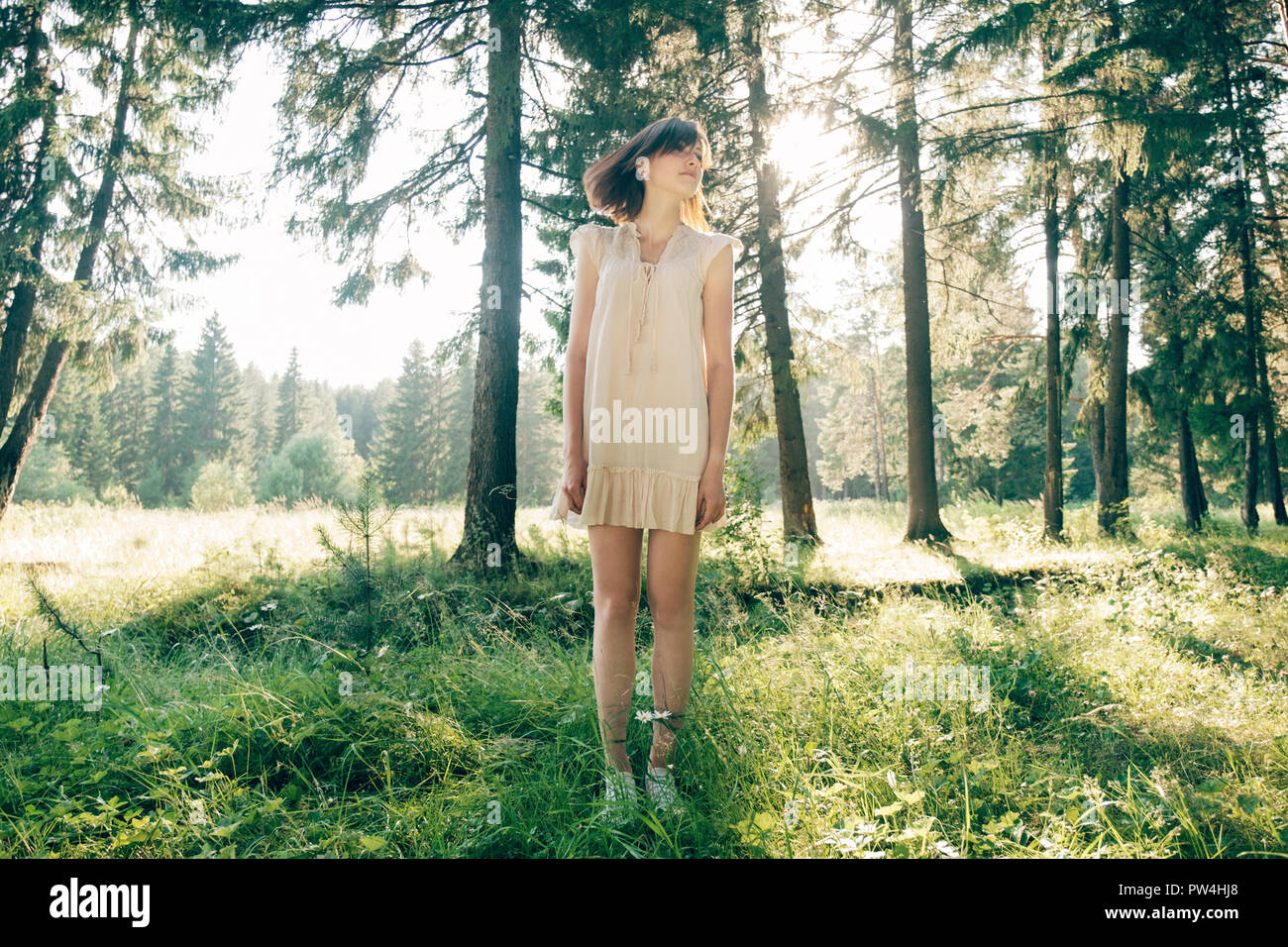 Per tutta la lunghezza della giovane donna in piedi sul campo erboso in foresta Foto Stock