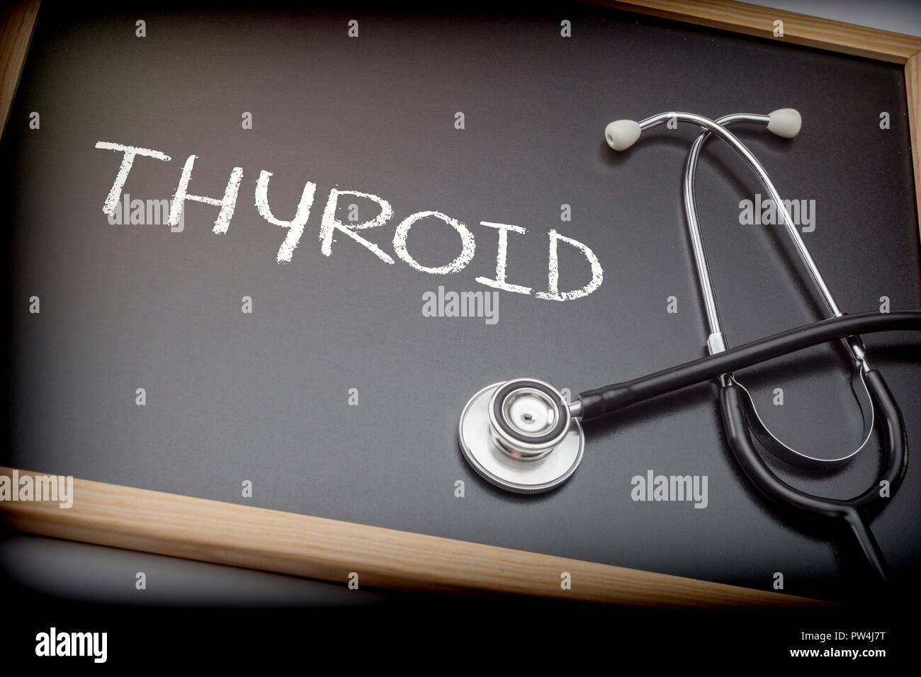 La parola scritta della tiroide in gesso su una lavagna nera accanto a uno stetoscopio, immagine concettuale Foto Stock