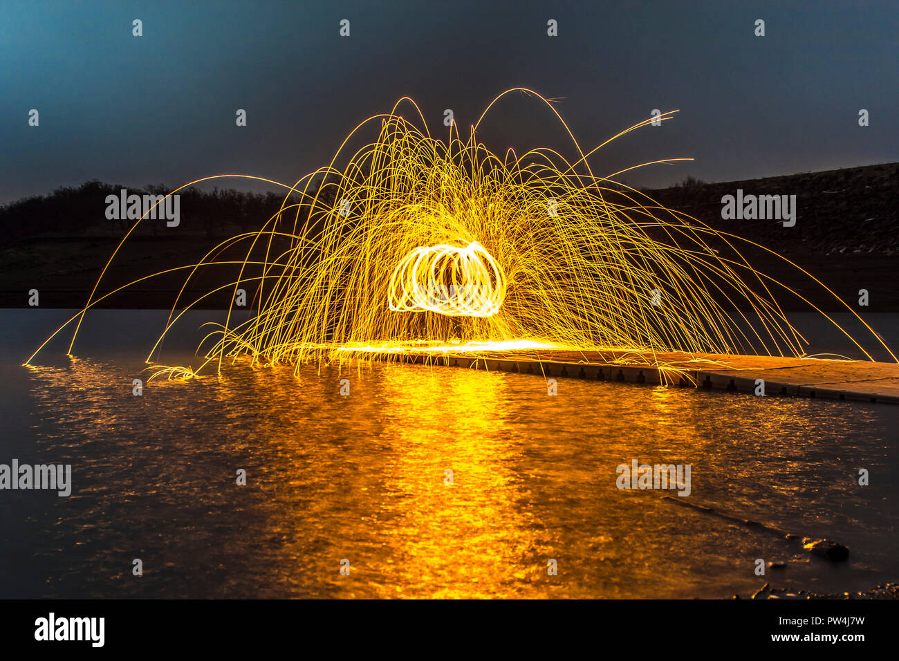 La masterizzazione di lana di acciaio durante la notte sul molo sul lago Foto Stock