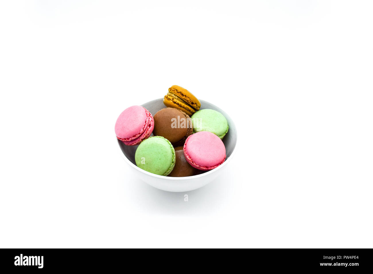 Macarons nella ciotola, dolci macaron colorati su sfondo bianco Foto Stock