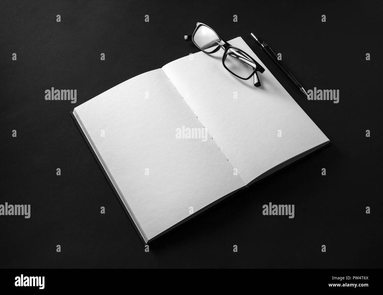 Mockup del fustellato aperto libro, matita e occhiali su sfondo nero. Foto Stock