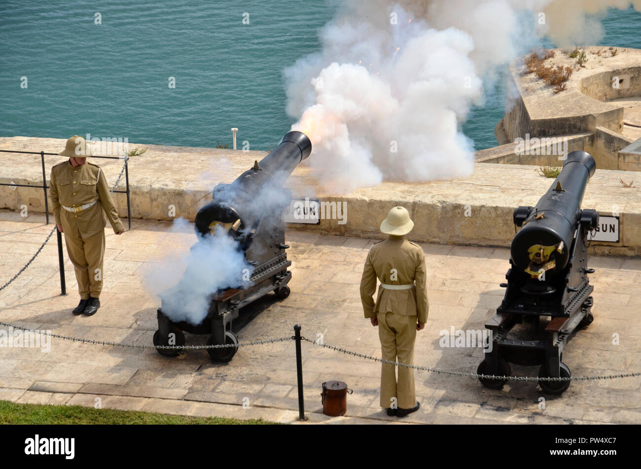 Lo sparo del cannone di mezzogiorno nella capitale Maltese di La Valletta.  La cerimonia si tiene ogni giorno alla batteria a salve in alto Barracca  gardens Foto stock - Alamy