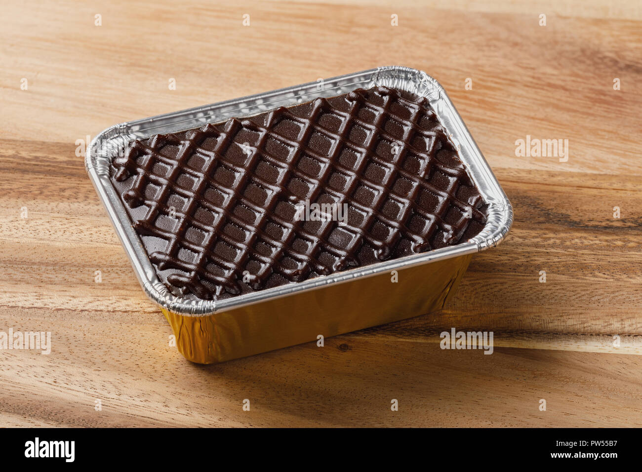 Torta al cioccolato in un foglio di alluminio il vassoio sul tavolo di legno o tagliere, deep focus immagine di impilamento Foto Stock
