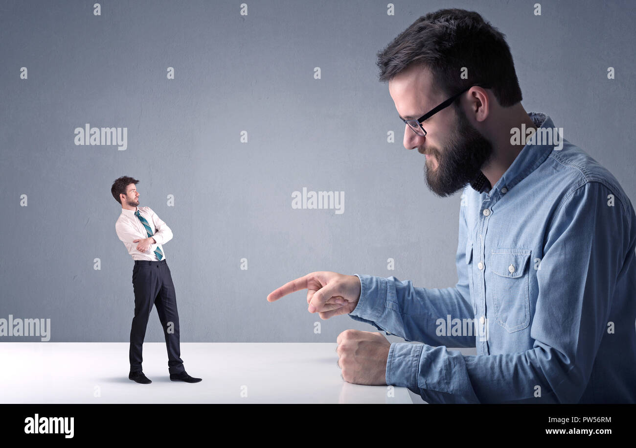 Giovane imprenditore professionale essendo arrabbiato con un altro imprenditore in miniatura Foto Stock