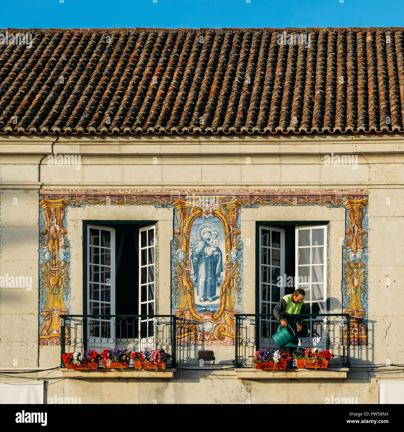 Cascais, Portogallo - Ott 12, 2018: Un uomo acque piante al balcone di Cascais Town Hall decorata con splendidi azulejos piastrelle portoghesi Foto Stock