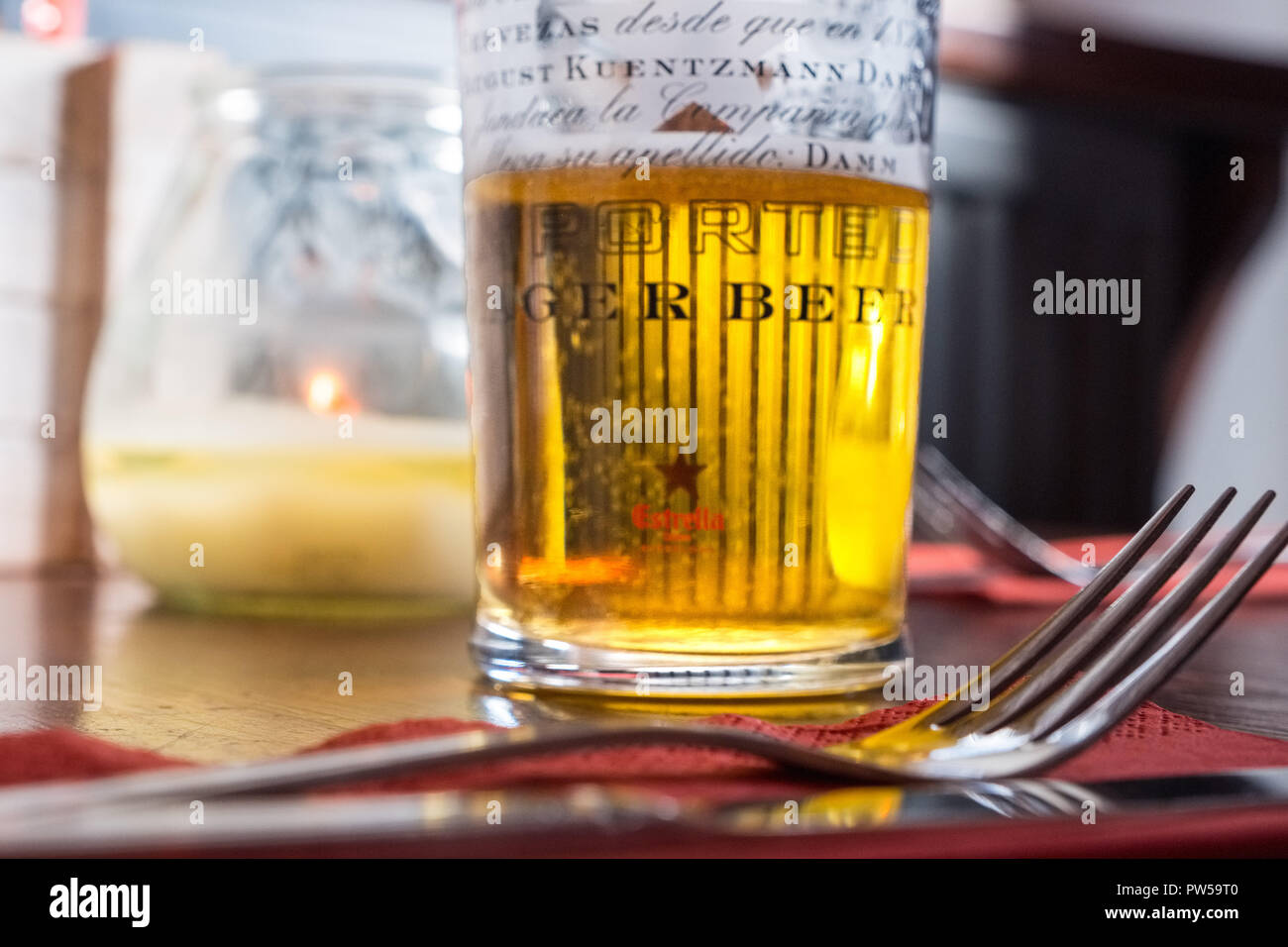 Mezza bevuto un bicchiere di birra lager e una forcella su un tavolo in un bar Foto Stock