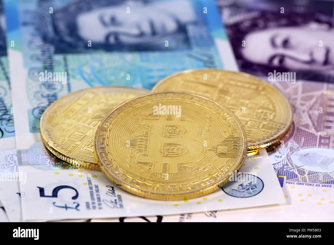 Tre cryptocurrency virtuale denaro Bitcoin monete d'oro sul Regno Unito sterlina inglese di banconote con le facce della regina Elisabetta II. Foto Stock