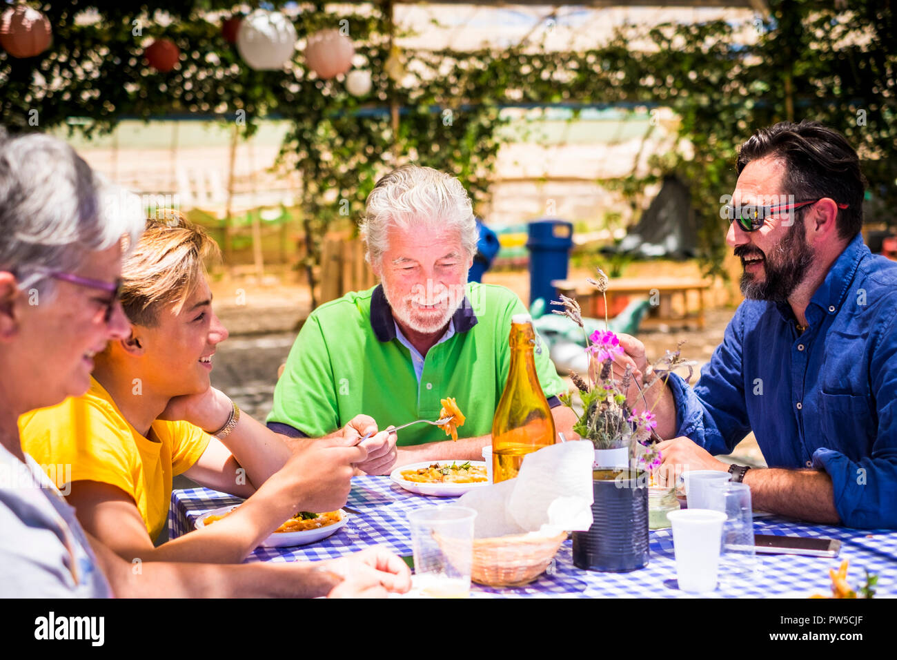 Famiglia caucasica a pranzo insieme durante una giornata di sole per divertirsi e sorridere mentre mangi la pasta italiana La cucina del cibo. ristorante luogo naturale con economici dis Foto Stock