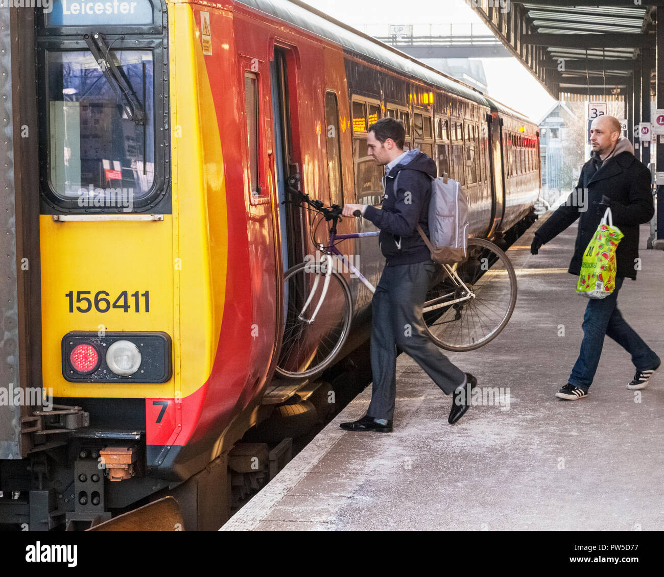 Un passeggero e un ciclista che trasportano una bicicletta per salire a bordo di un treno a Lincoln stazione ferroviaria, England, Regno Unito Foto Stock