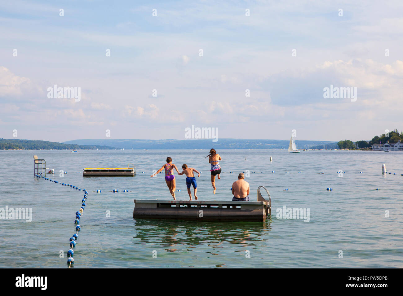 Una famiglia salti in Lago Skaneateles, Skaneateles, New York, Stati Uniti d'America, 14 giugno 2013. Foto Stock