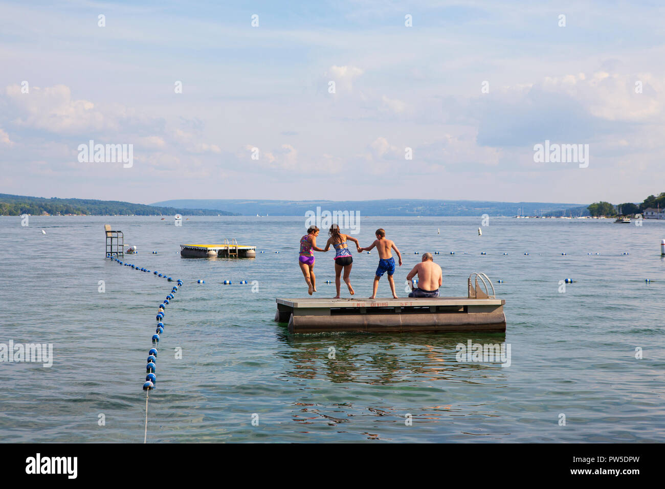 Una famiglia salti in Lago Skaneateles, Skaneateles, New York, Stati Uniti d'America, 14 giugno 2013. Foto Stock